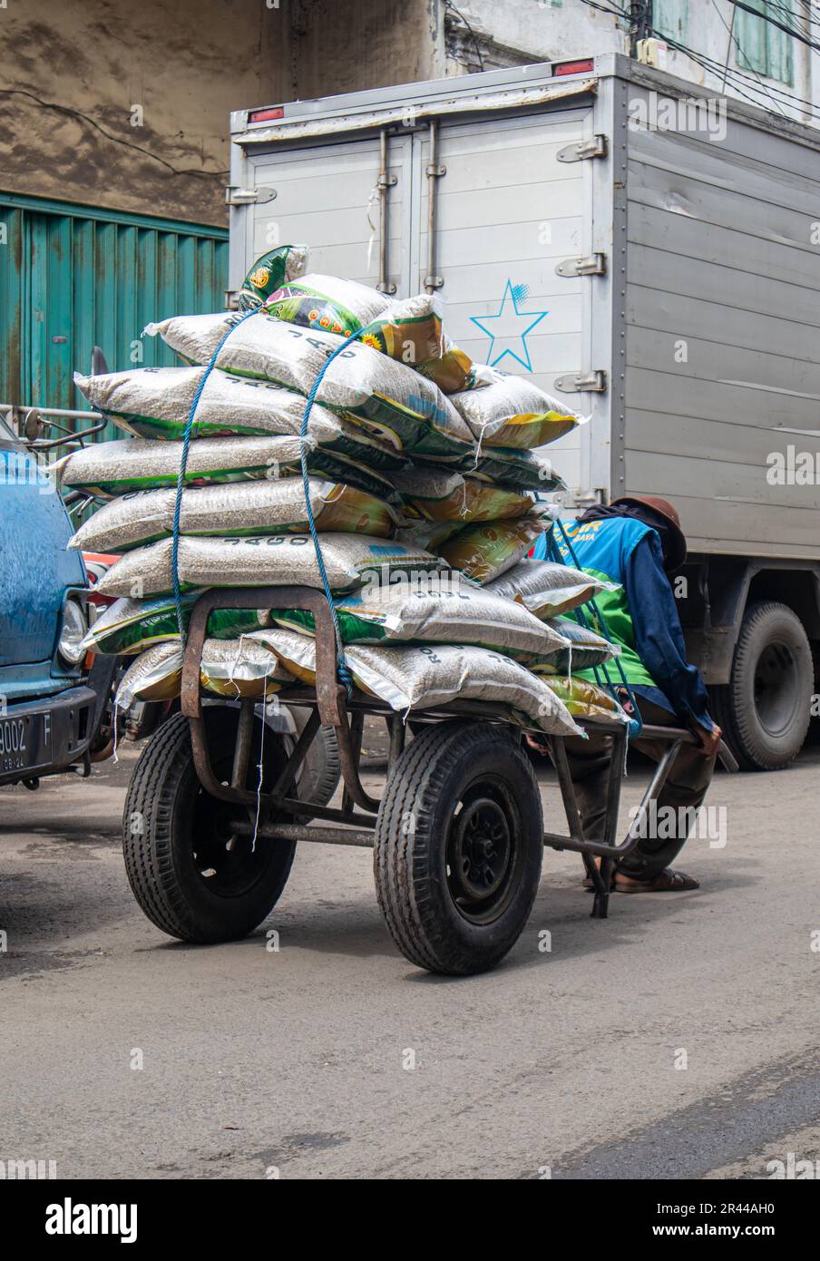 un uomo operaio trasporta merci con un carrello in un mercato tradizionale Foto Stock