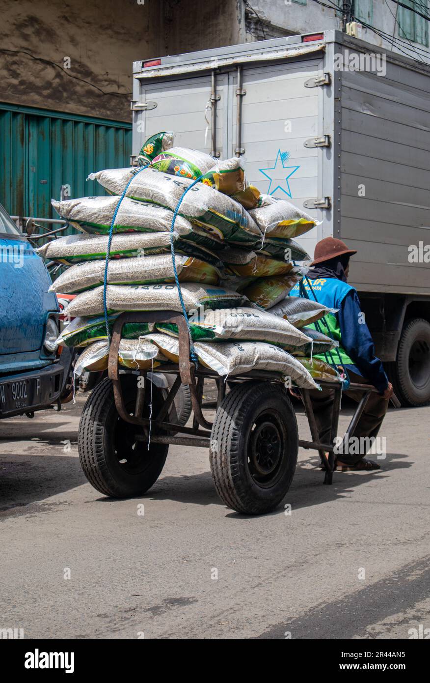 un uomo operaio trasporta merci con un carrello in un mercato tradizionale Foto Stock