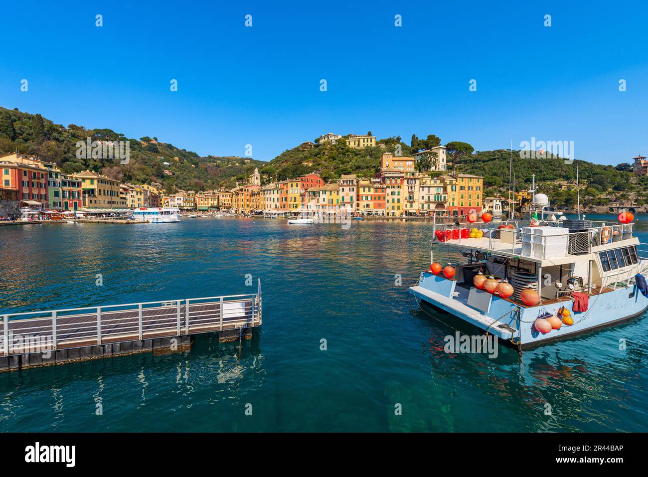 Molo in legno e barca da pesca ormeggiata nel famoso porto di Portofino, lussuosa località turistica della provincia di Genova, Liguria, Italia, Europa. Casa colorata Foto Stock