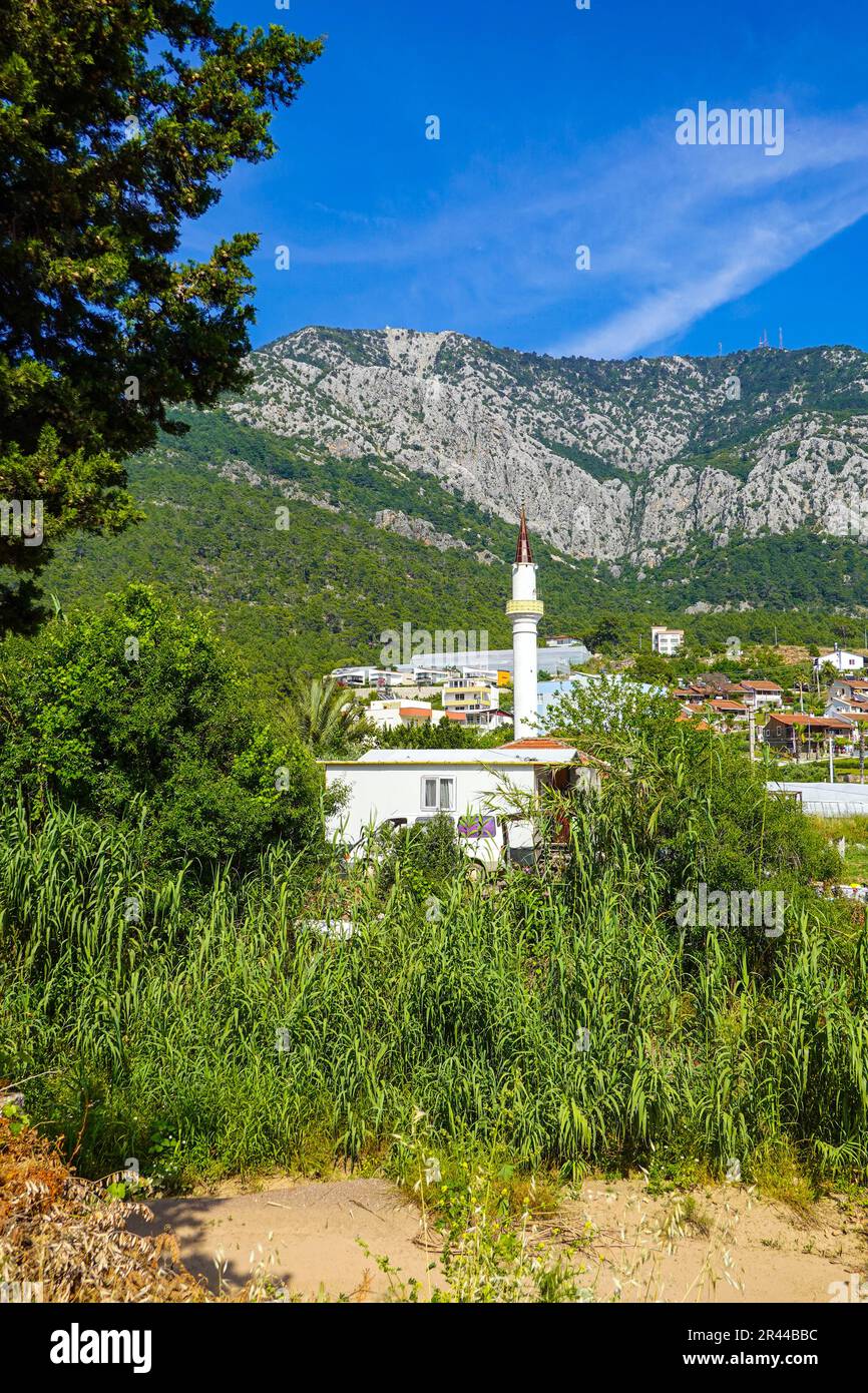 Minareto bianco una parte della moschea musulmana circondata da montagne, a Karaoz, Kumluca, Turchia Foto Stock