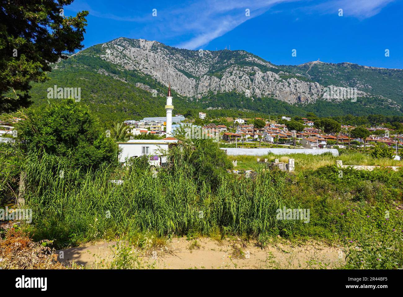 Minareto bianco una parte della moschea musulmana circondata da montagne, a Karaoz, Kumluca, Turchia Foto Stock