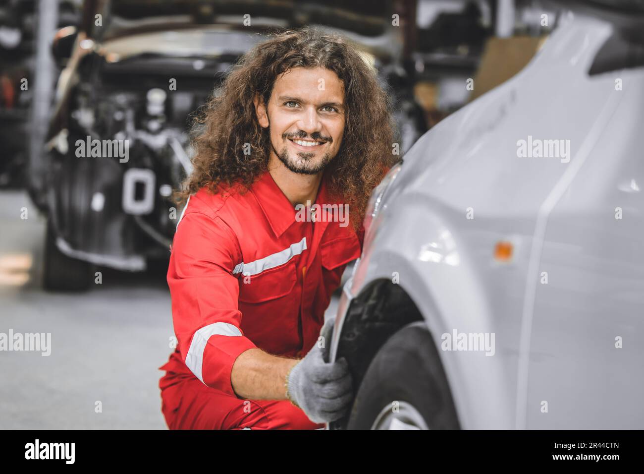 Hispanic lavoratore di personale maschile lavoro in officina auto felice sorridere godere di lavoro di assistenza sostituzione pneumatici auto Foto Stock