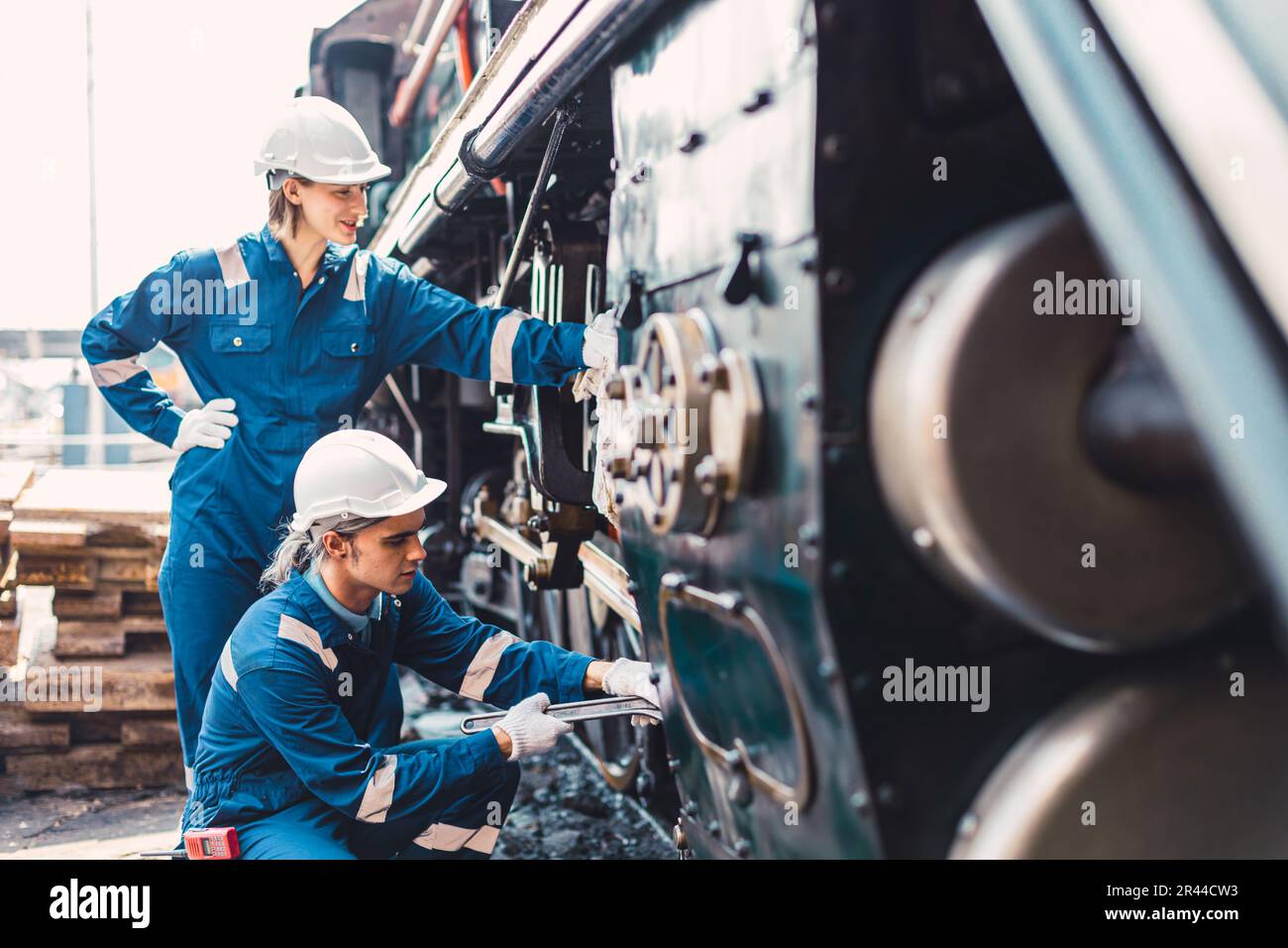 Train Engineer team di lavoro servizio manutenzione vecchio sporco vintage classico locomotiva a vapore in officina di riparazione treni alla stazione ferroviaria. Foto Stock