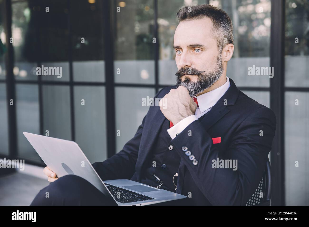 Uomo d'affari ispanico latino indiano adulto maschio baffi e barba pensiero intelligente con laptop seduto all'aperto Foto Stock