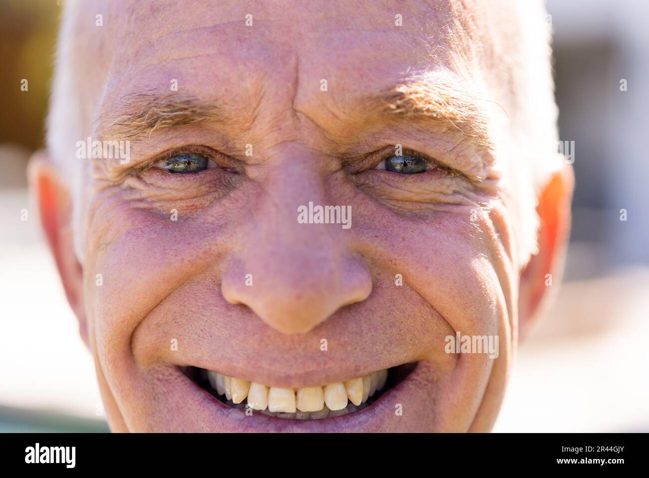 Ritratto primo piano di felice uomo caucasico anziano guardando la macchina fotografica e sorridendo al sole Foto Stock