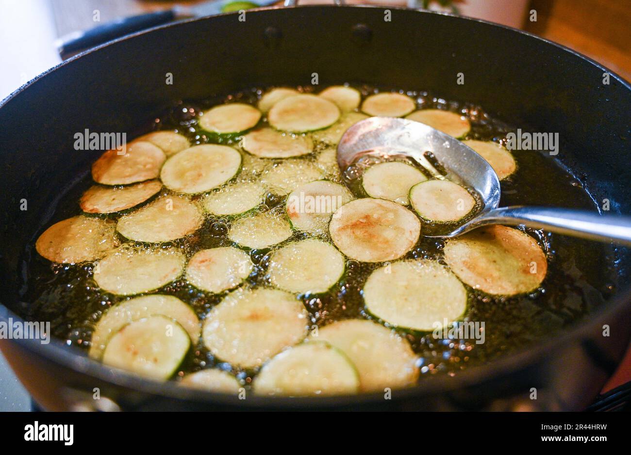 Friggere o rosolare le fette di zucchine o zucchine in olio di girasole pronte per l'uso in un piatto di pasta italiana Foto Stock