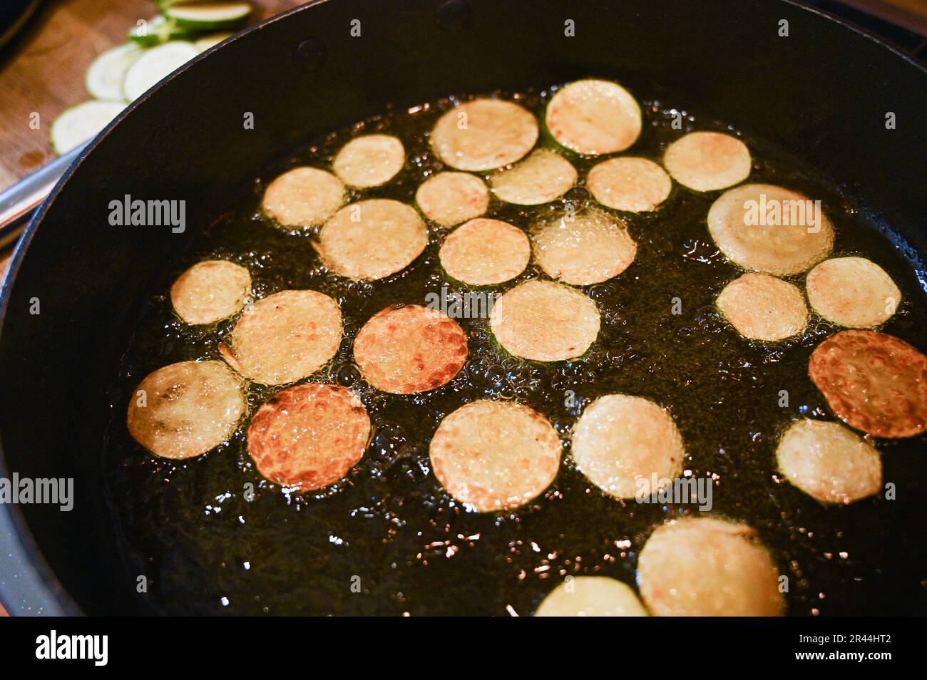 Friggere o rosolare le fette di zucchine o zucchine in olio di girasole pronte per l'uso in un piatto di pasta italiana Foto Stock