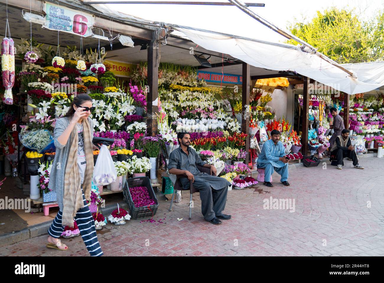 Una donna passeggia davanti a un negozio di fiori vicino al mercato del quartiere, islamabad, pakistan. Foto Stock