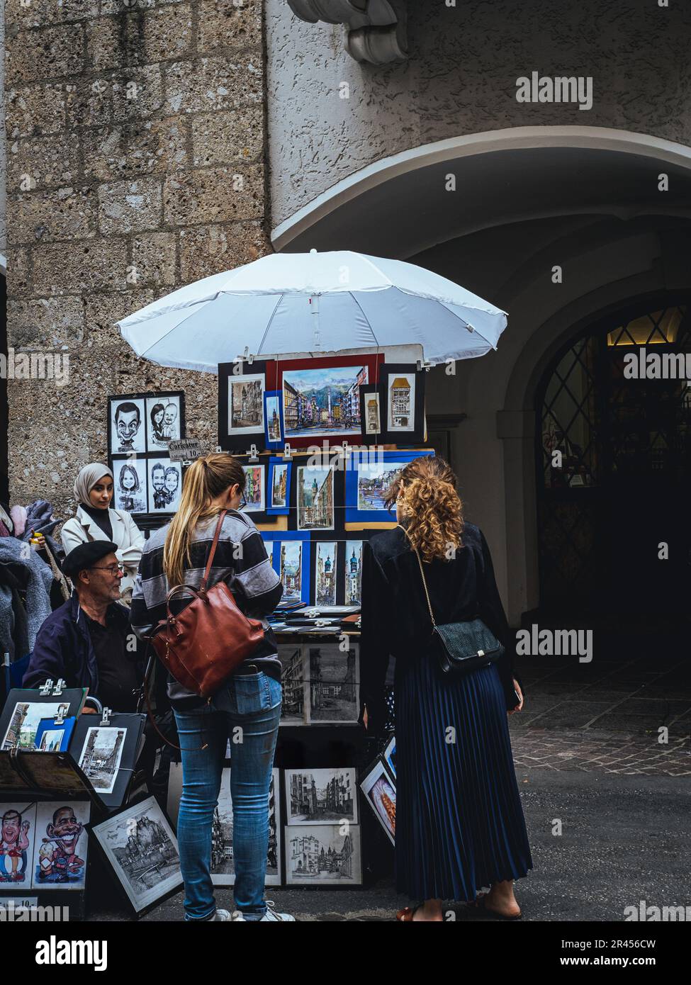 Artista di strada pittore caricatura disegno vendere souvenir nel centro storico medievale turisti persone in cerca di acquistare venditori di strada Innsbruck, Austria, Tyr Foto Stock