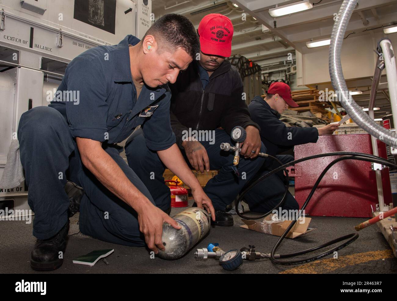 230202-N-DP708-1202 OCEANO PACIFICO (2 febbraio 2023) danno Controlman Fireman Fernando Aguilera, a sinistra, un nativo di Los Angeles, California, danno Controlman Fireman Xavier Thomas, centro, un nativo di Tampa, Fla., E danni Controlman 2nd Classe Reginald Herrera, un nativo di Fresno, Calif., eseguire la manutenzione su un compressore d'aria nella baia hangar a bordo di Nimitz-classe portaerei USS Carl Vinson (CVN 70). Vinson sta attualmente conducendo operazioni marittime di routine. Foto Stock