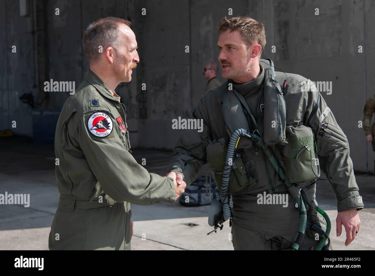 STATI UNITI Air Force Lt. Col. Shaun Loomis, 480th Comandante dello Squadrone del combattente Expeditionary, a sinistra, scuote le mani con gli Stati Uniti Michael Mickus, 355th comandante dello squadrone del combattente espeditionario, alla base aerea di Kadena, Giappone, 28 marzo 2023. Mentre si è schierato nella Keystone del Pacifico, il F-35s lavorerà in collaborazione con altre unità di combattimento a Kadena per assicurare le capacità costanti del combattente. Foto Stock