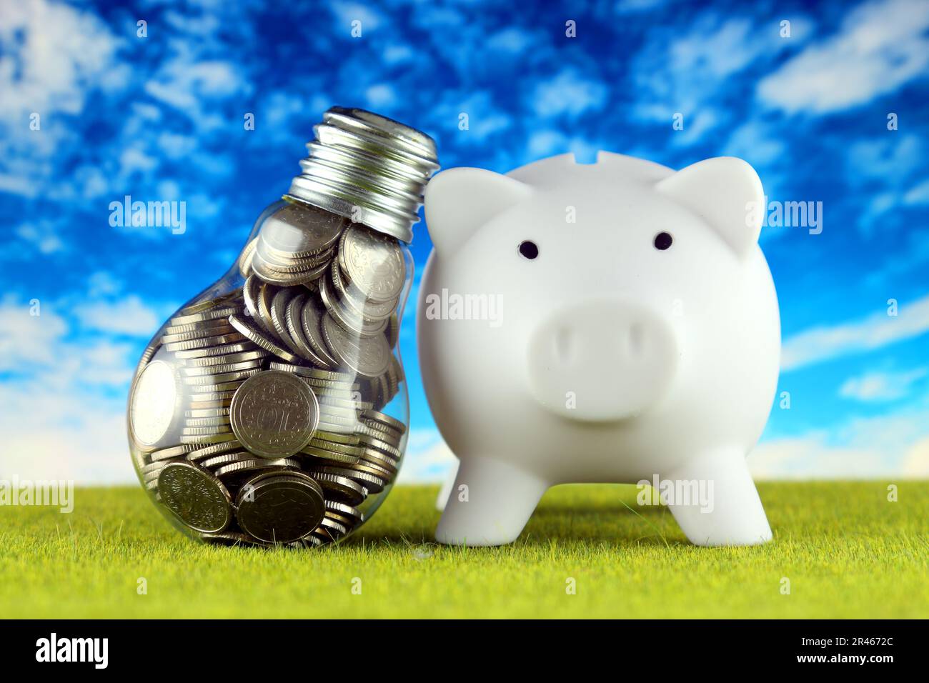 Monete all'interno della lampadina e del banco di porcellini. Eco-verde energia rinnovabile concetto. I prezzi dell'elettricità, il risparmio energetico in famiglia. Foto Stock