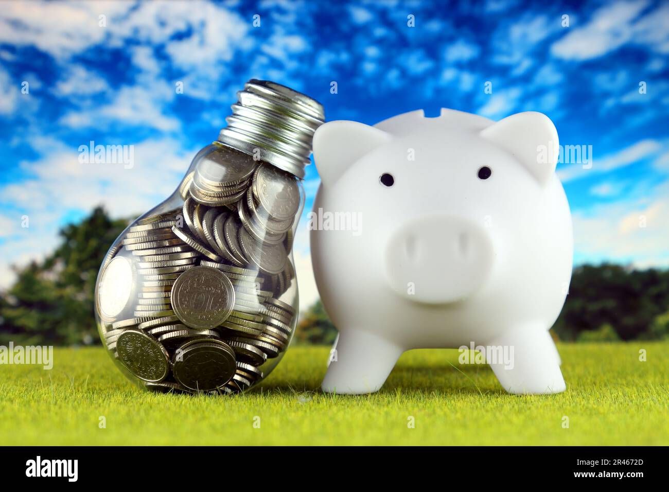 Monete all'interno della lampadina e del banco di porcellini. Eco-verde energia rinnovabile concetto. I prezzi dell'elettricità, il risparmio energetico in famiglia. Foto Stock