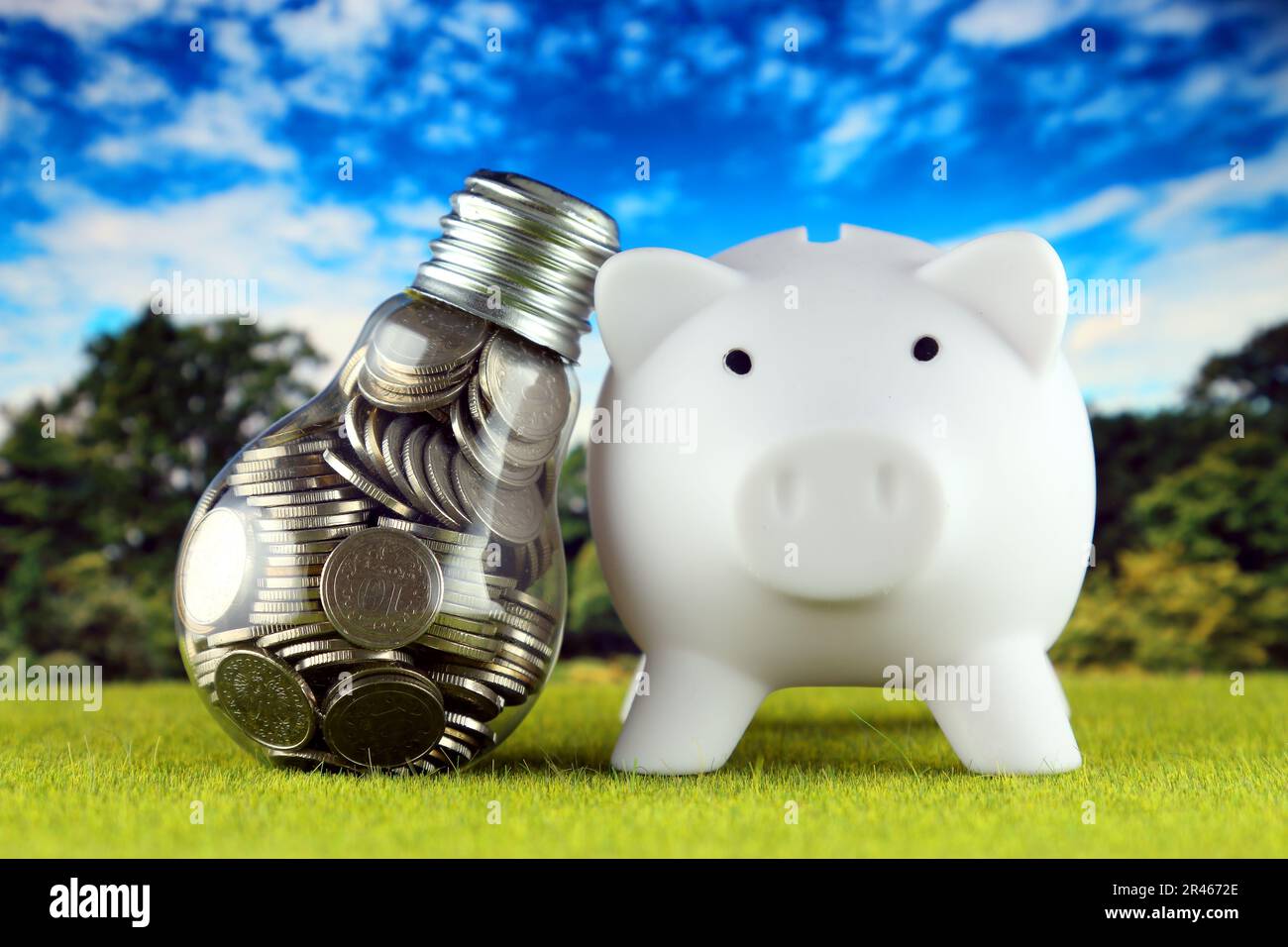 Monete all'interno della lampadina e del banco di porcellini. Eco-verde energia rinnovabile concetto. I prezzi dell'elettricità, il risparmio energetico in famiglia. Foto Stock