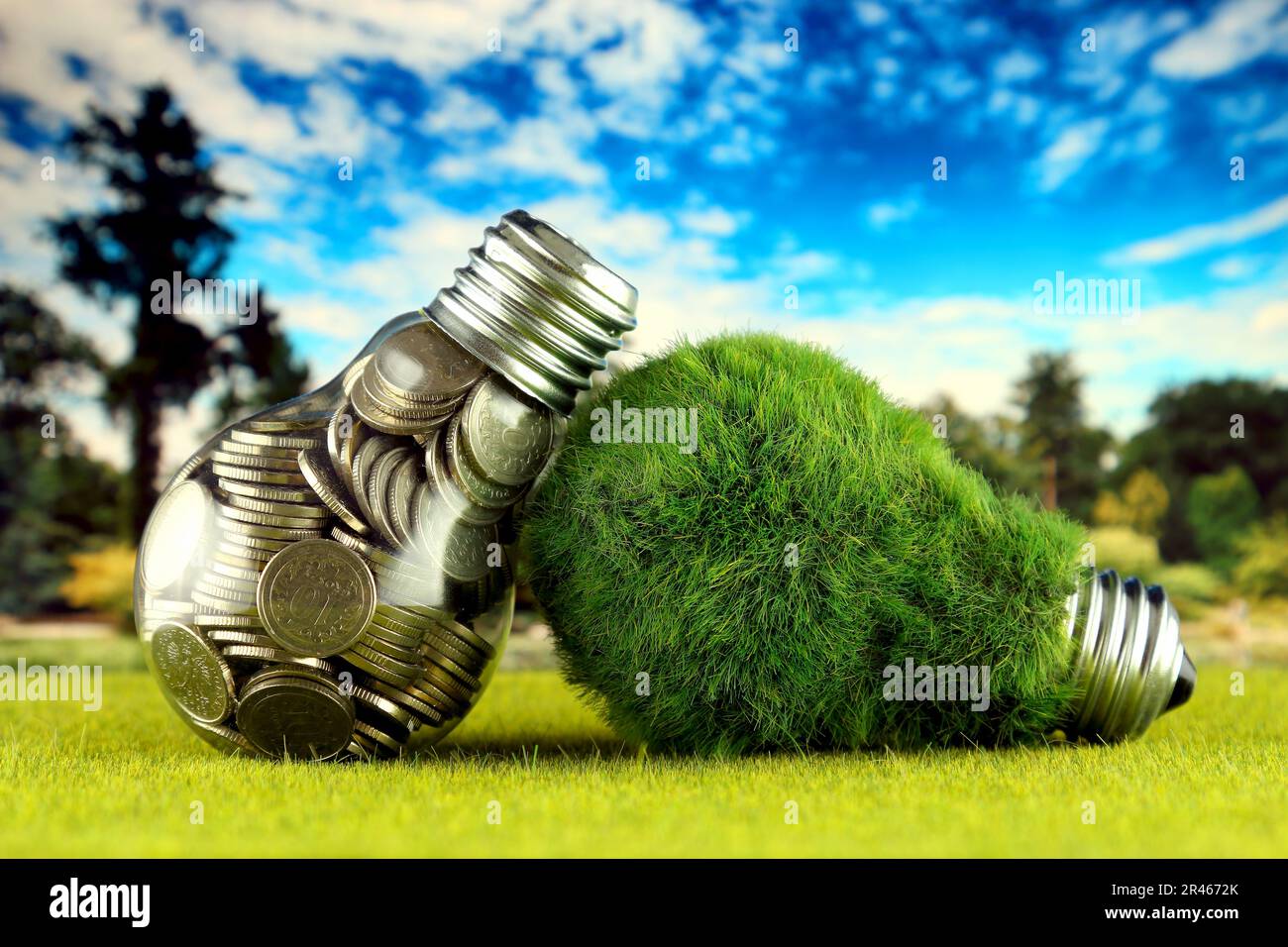 Monete all'interno della lampadina e lampadina verde eco con erba. Concetto di energia rinnovabile. I prezzi dell'elettricità, il risparmio energetico in famiglia. Foto Stock