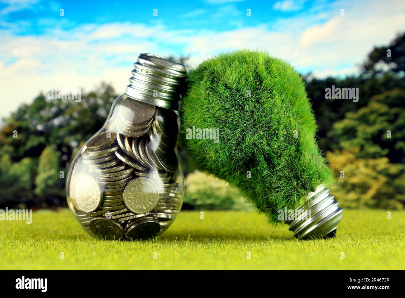 Monete all'interno della lampadina e lampadina verde eco con erba. Concetto di energia rinnovabile. I prezzi dell'elettricità, il risparmio energetico in famiglia. Foto Stock