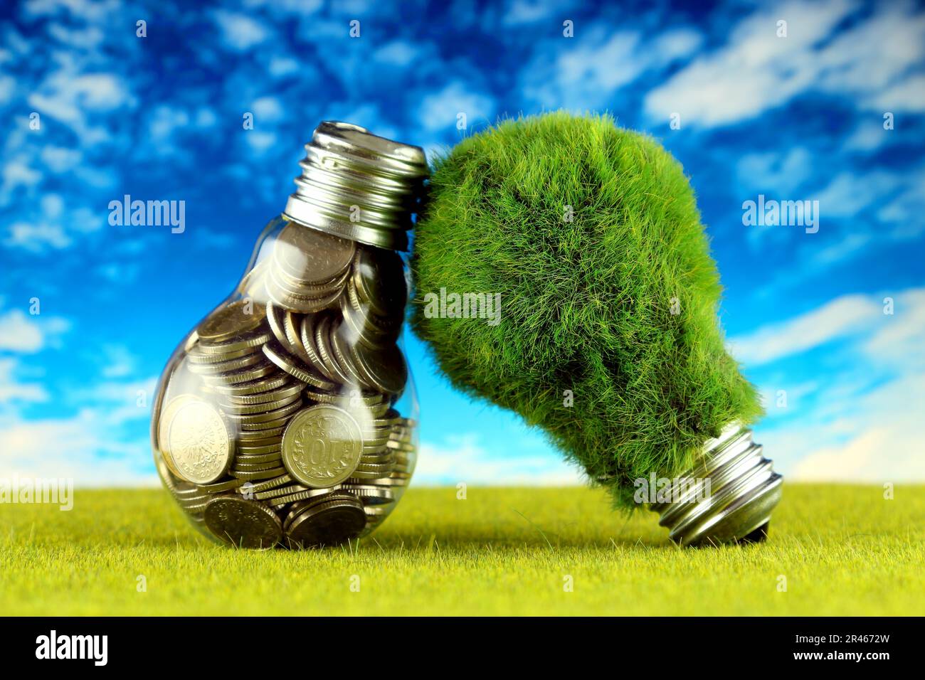 Monete all'interno della lampadina e lampadina verde eco con erba. Concetto di energia rinnovabile. I prezzi dell'elettricità, il risparmio energetico in famiglia. Foto Stock