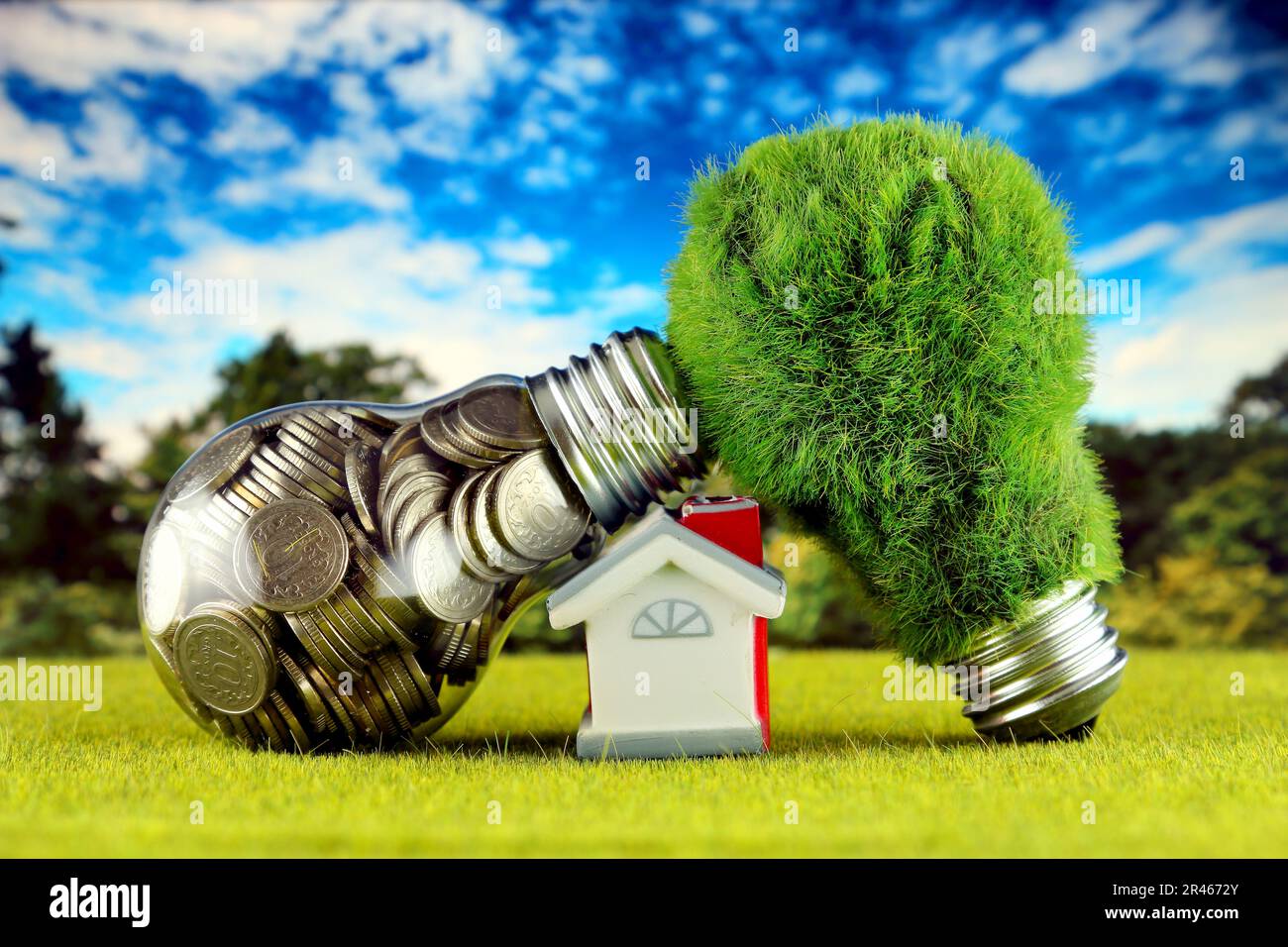 Monete all'interno della lampadina, lampadina verde eco con erba e casa in miniatura. Concetto di energia rinnovabile. I prezzi dell'elettricità, il risparmio energetico nelle ore Foto Stock