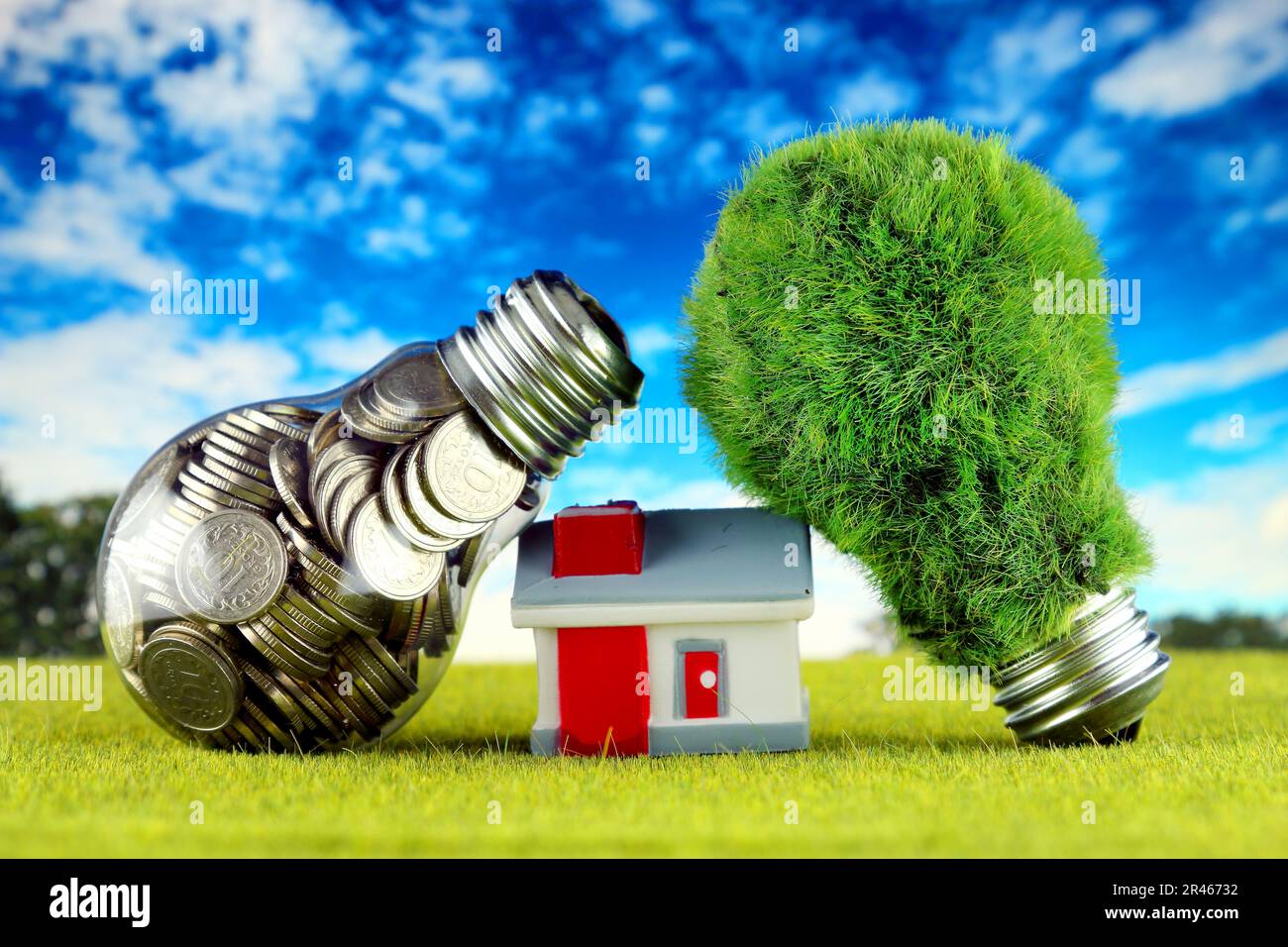 Monete all'interno della lampadina, lampadina verde eco con erba e casa in miniatura. Concetto di energia rinnovabile. I prezzi dell'elettricità, il risparmio energetico nelle ore Foto Stock