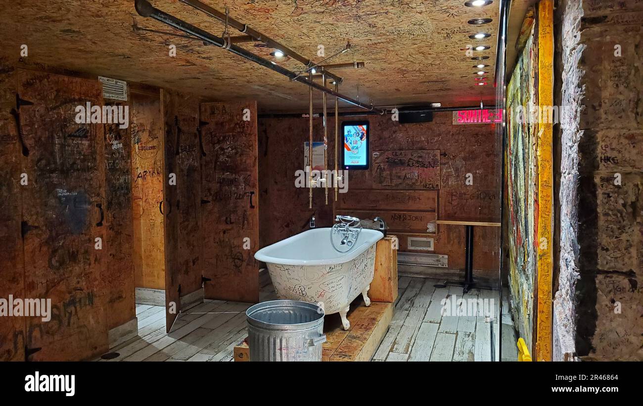 Un interno scuola-bagno in stile vintage, con pareti giallo opaco, un pavimento piastrellato, un lavandino e servizi igienici Foto Stock