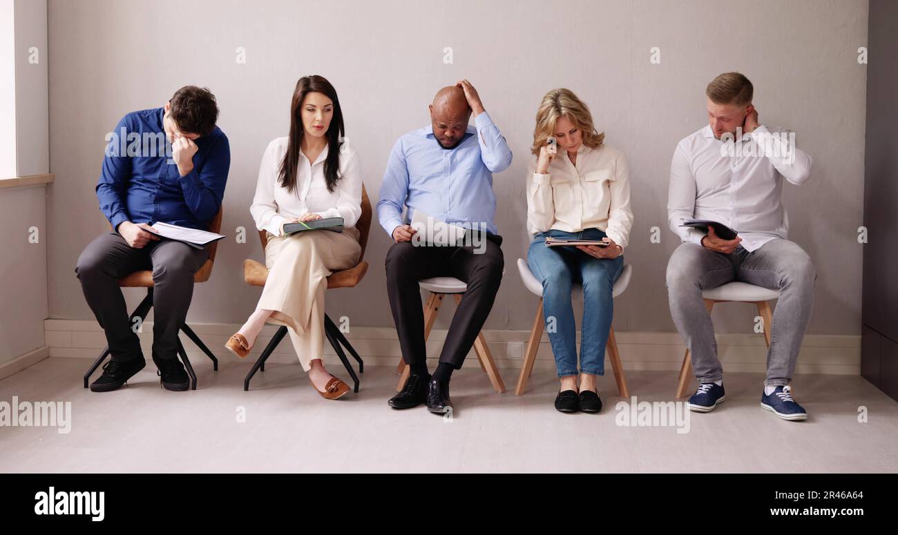 La gente di affari sono annoiarsi mentre è seduto su una sedia in attesa per il colloquio di lavoro in ufficio Foto Stock