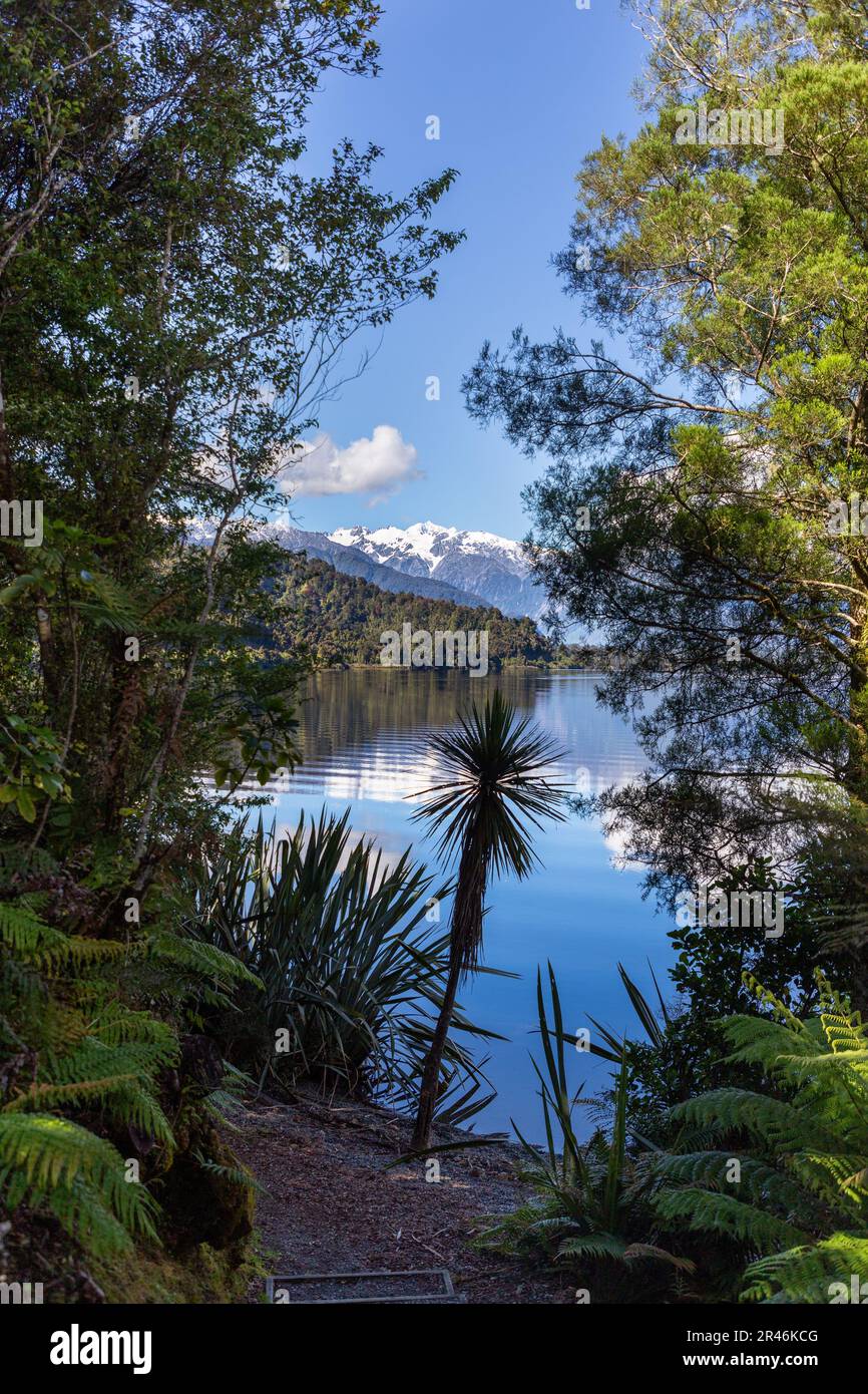 Idilliaco paesaggio del tranquillo Lago Mapourika che riflette le maestose montagne della Nuova Zelanda Foto Stock