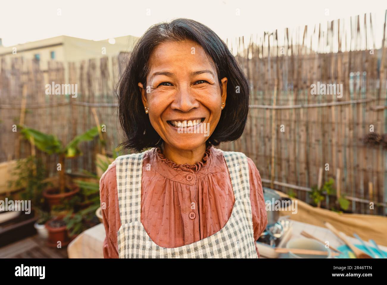 Felice donna tailandese che ha divertente sorridere di fronte alla macchina fotografica mentre preparano la ricetta del cibo nel patio della casa Foto Stock