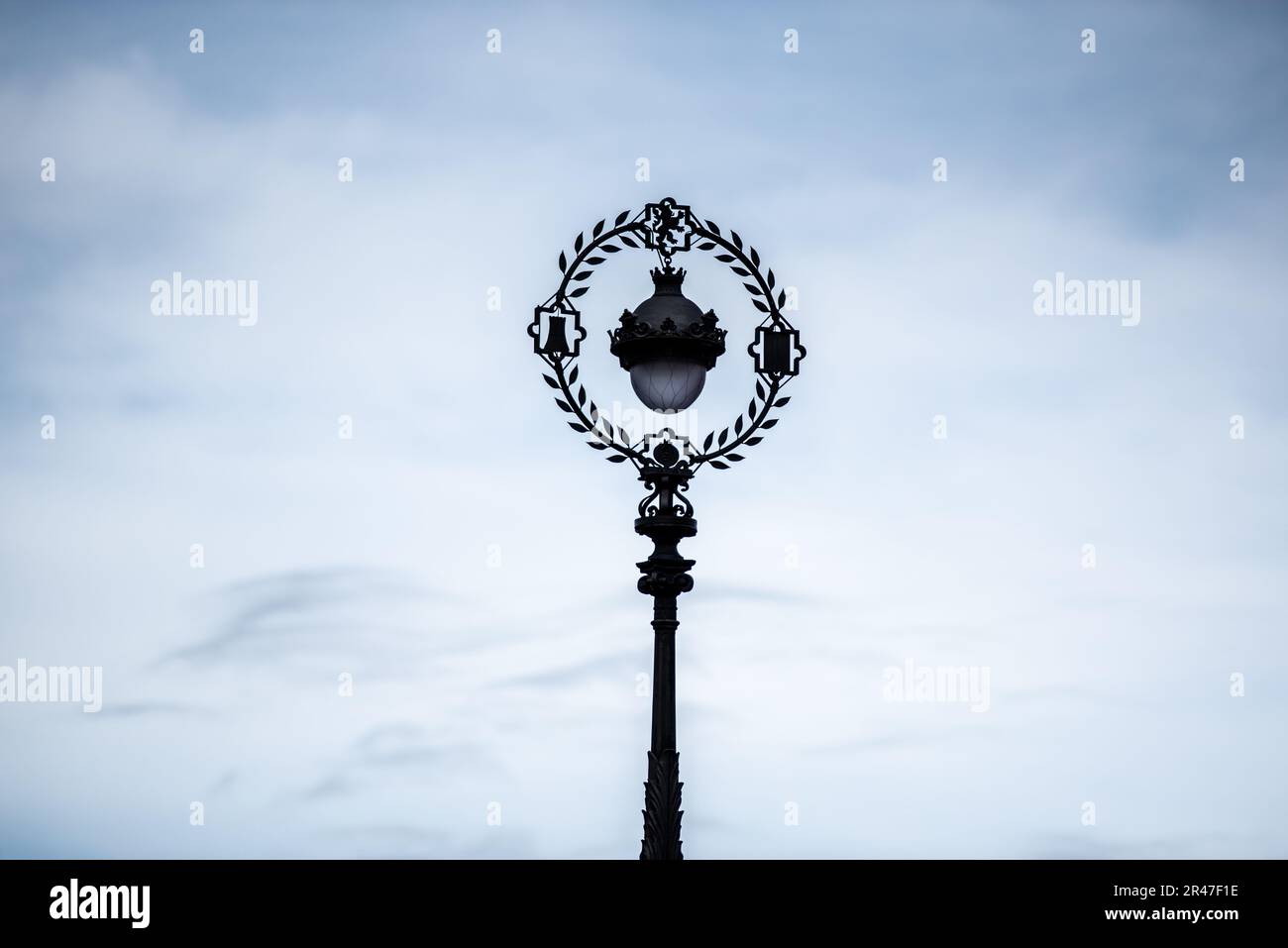 Un'alta lampada da strada bianca che si erge sullo sfondo di un cielo nuvoloso blu Foto Stock