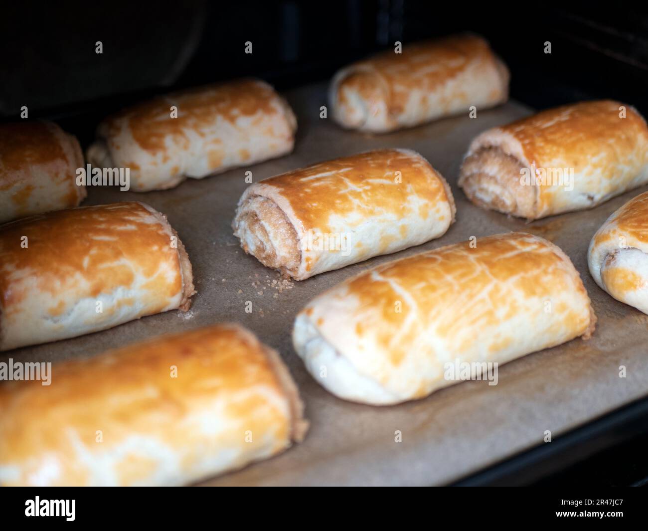 Panini appena sfornati su carta da forno, fuoco selettivo. Panini dorati preparati in forno. Pasto fatto in casa Foto Stock
