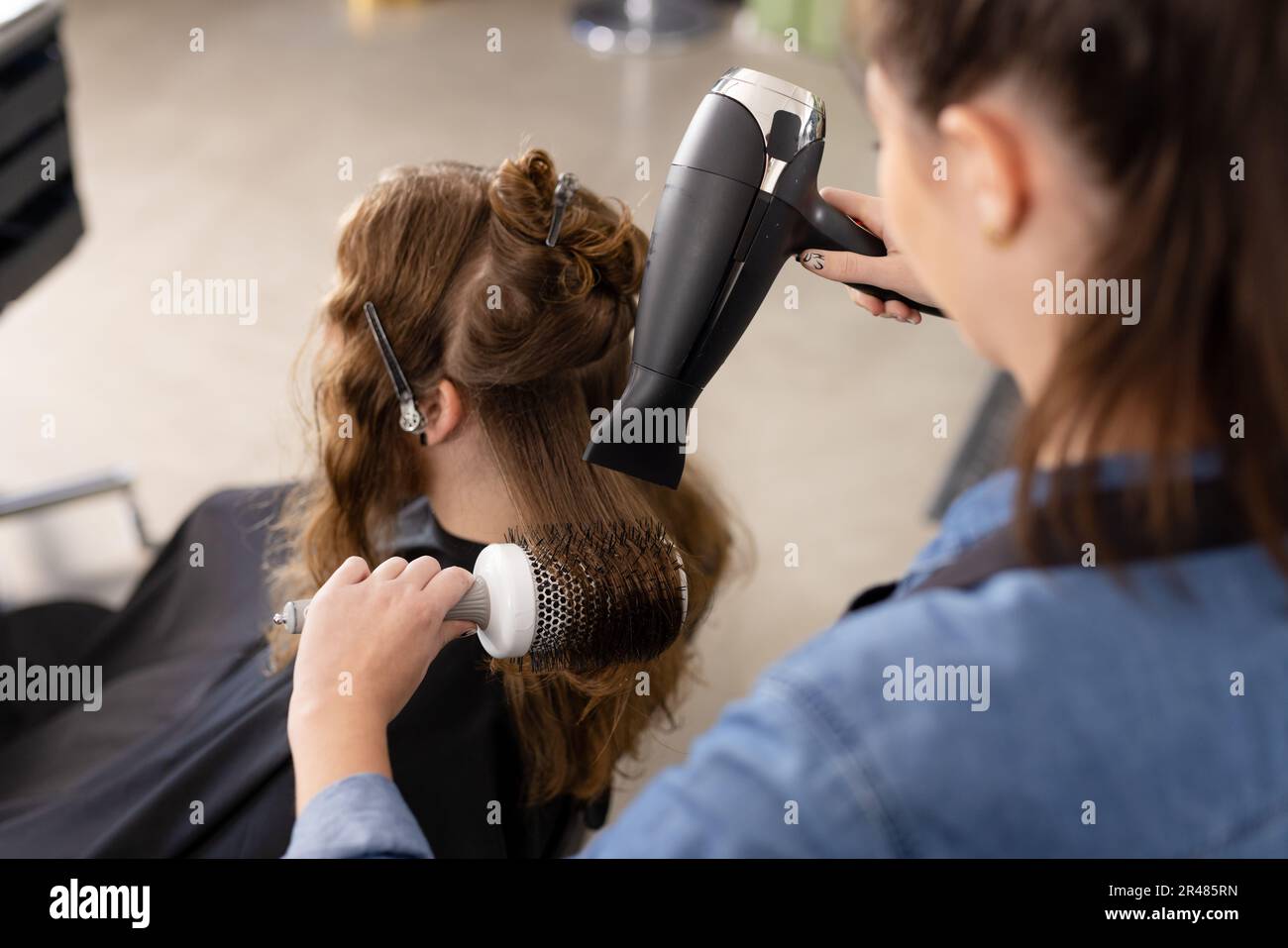 Donna caucasica acconciatura capelli di cliente femminile con asciugacapelli e pennello presso parrucchiere Foto Stock