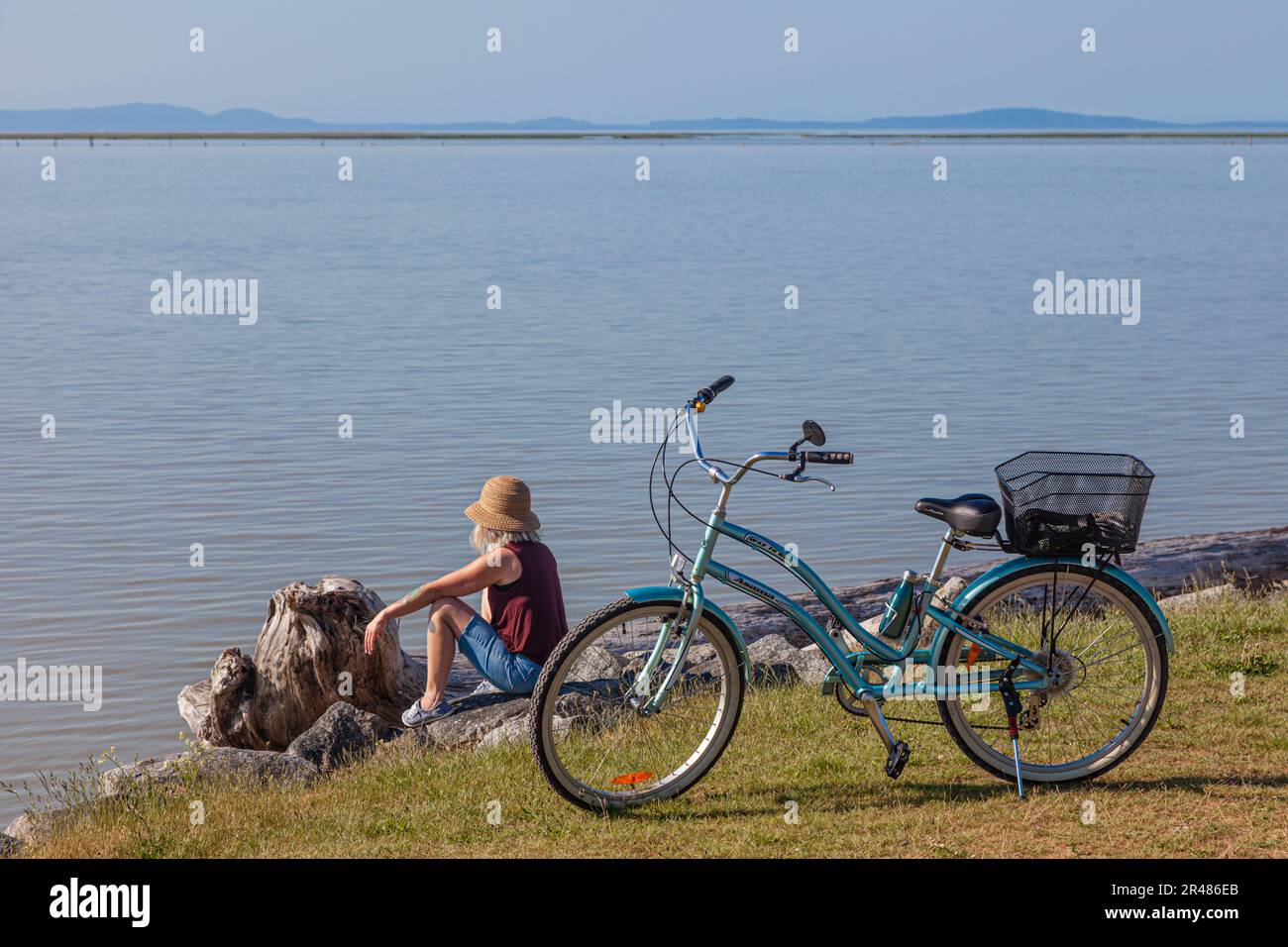 Una donna con la sua bici che guarda sopra l'estuario del fiume Fraser a Steveston British Columbia Canada Foto Stock