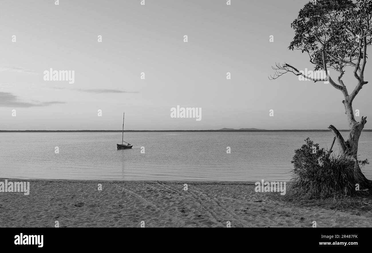 La sensazione di solitudine di una barca solitaria sulle calme acque del lago Cootharaba in una mattina di primo autunno Foto Stock