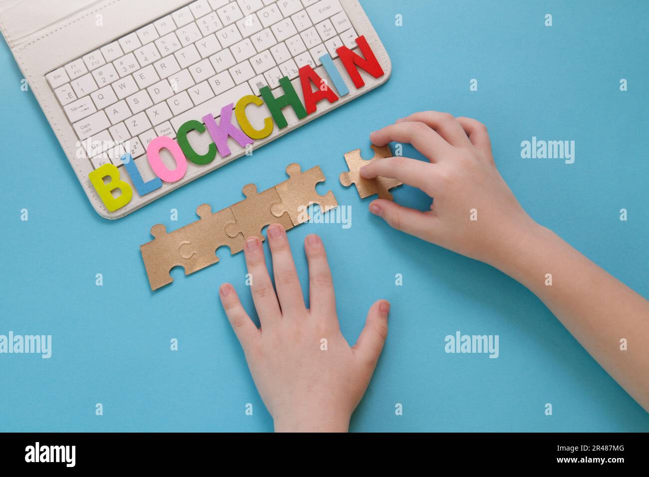 Istruzione. Blockchain per bambini. Finanza del gioco. Bambini mano muove puzzle, computer portatile su sfondo blu. Tecnologia mineraria o blockchain. Decentralizzato Fi Foto Stock