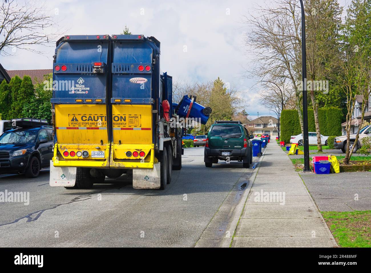 Collegamenti per rifiuti del Canada autocarro per raccolta rifiuti residenziale con sistema a mani libere che raccoglie rifiuti in Maple Ridge, B. C., Canada. Foto Stock