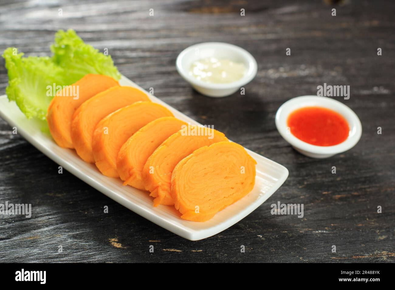 Tamagoyaki, omeletto di uovo laminato giapponese su tavola di legno. Servito con salsa e maionese Foto Stock