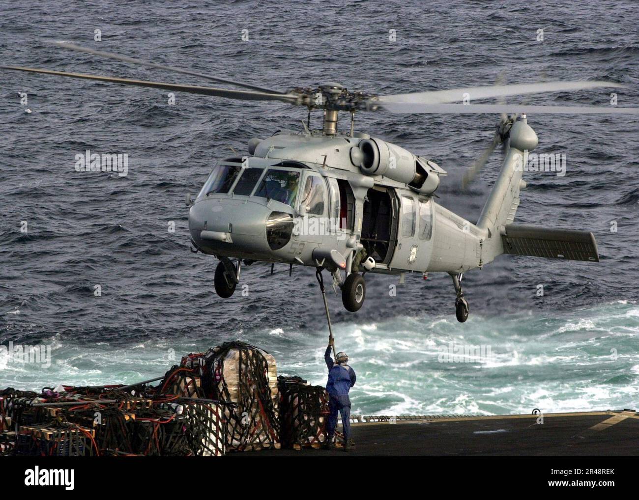 US Navy Un elicottero SH-60 ''Sea Hawk'' assegnato a Helicopter Combat Support Squadron Five (HC-5) si prepara a ricevere un pallet caricato con imbracatura Foto Stock