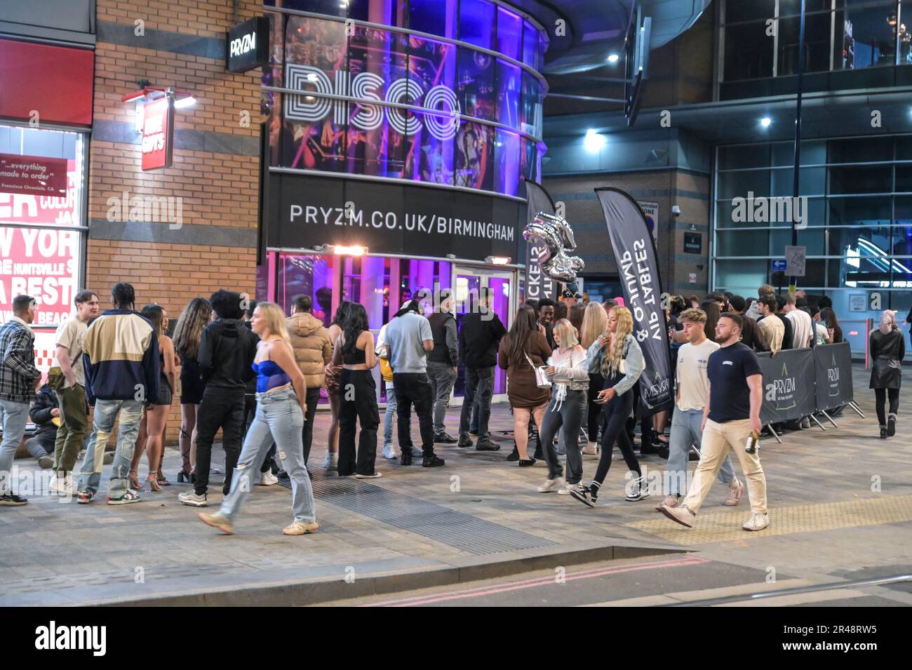 Broad Street, Birmingham, 26th maggio 2023 - i Rivenditori si accodano per entrare nel nightclub PYZM sulla Broad Street di Birmingham il venerdì sera per godersi la terza festa del mese. La maggior parte dei partygoers hanno indossato i vestiti skimpy dopo godere una giornata di tempo caldo malgrado le temperature che si tuffano alla notte. All'esterno si formarono grandi code, tra cui PYZM, Rosies e Popworld. Gruppi di amici hanno posato per una foto mentre il partito la notte via sulla festa della Banca di primavera. Credit: Stop Press Media/Alamy Live News Foto Stock