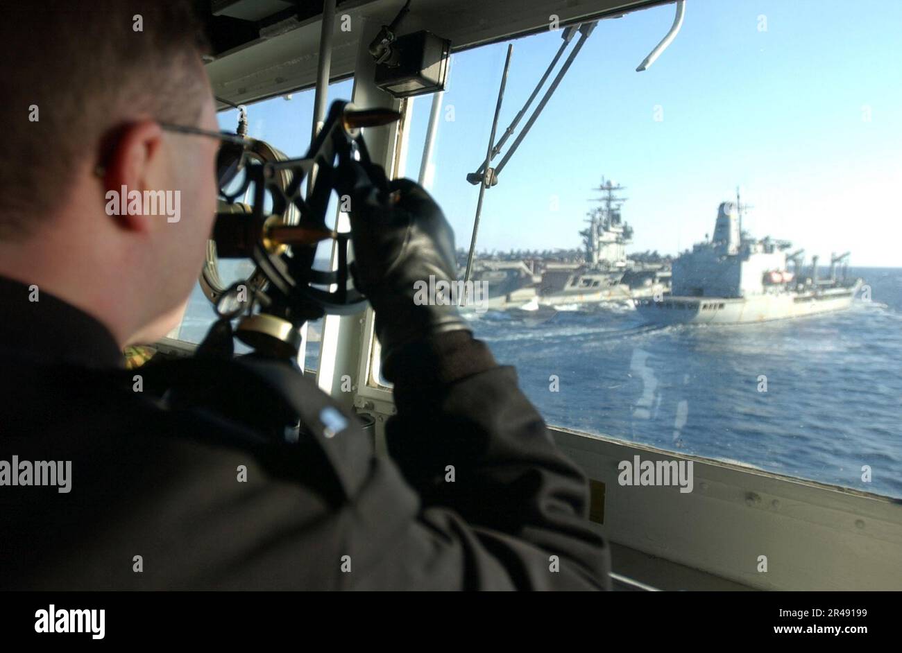 US Navy Un membro dell'equipaggio sul ponte della nave utilizza un rilevatore di distanza a stadi in stile sestante per verificare la distanza tra le navi durante un rifornimento in mare Foto Stock