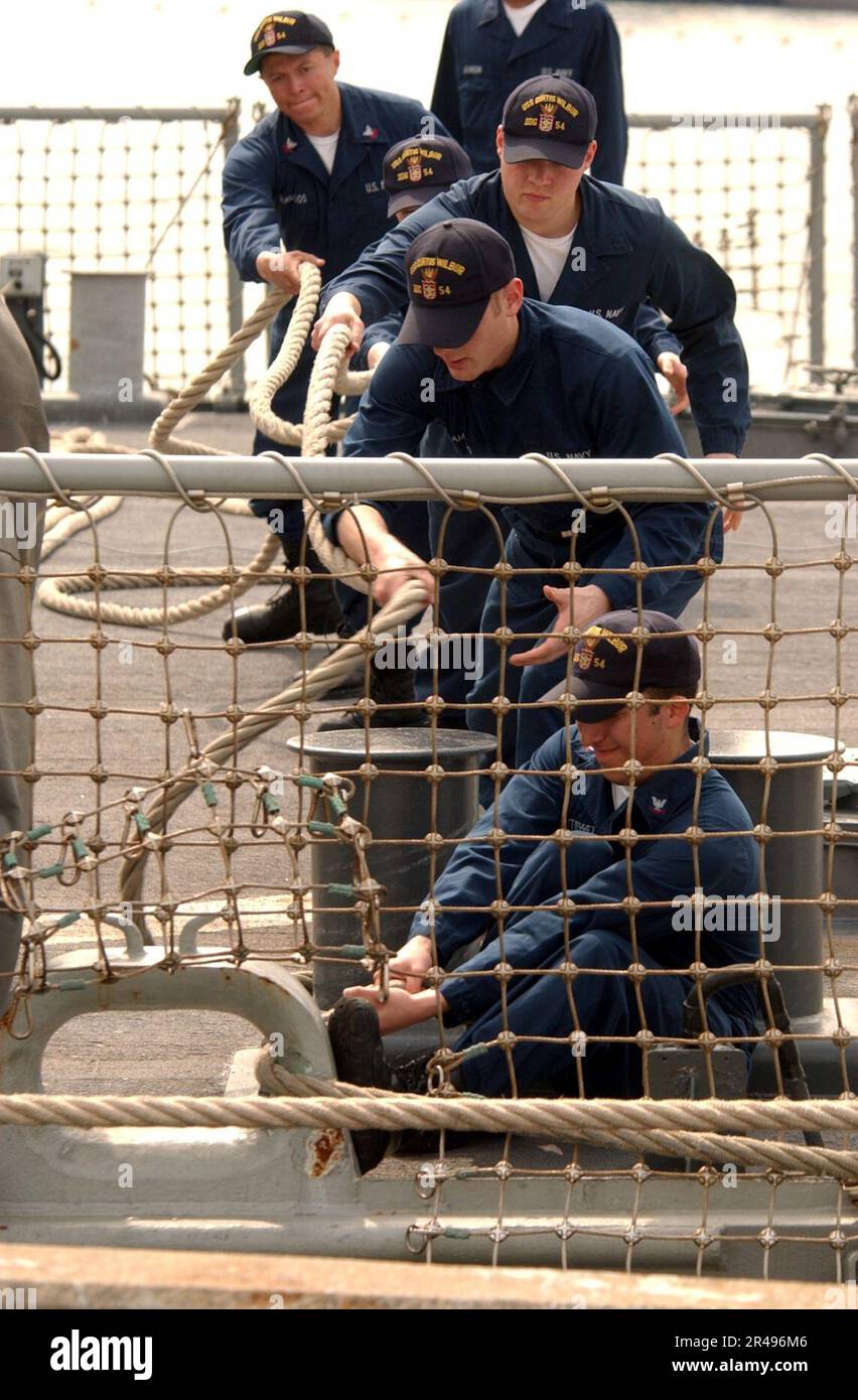 I marinai DELLA US Navy a bordo della USS Curtis Wilbur (DDG 54) attrarano una delle sue linee di ormeggio dopo il ritorno da un lavoro in mare Foto Stock