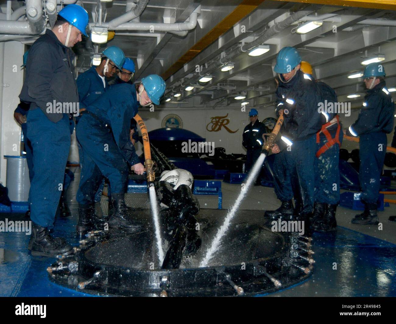 I marinai della Marina STATUNITENSE spruzzano acqua su una catena di ancoraggio per pulire il sale mentre viene tirato fuori dal mare a bordo della USS Theodore Roosevelt (CVN 71) Foto Stock