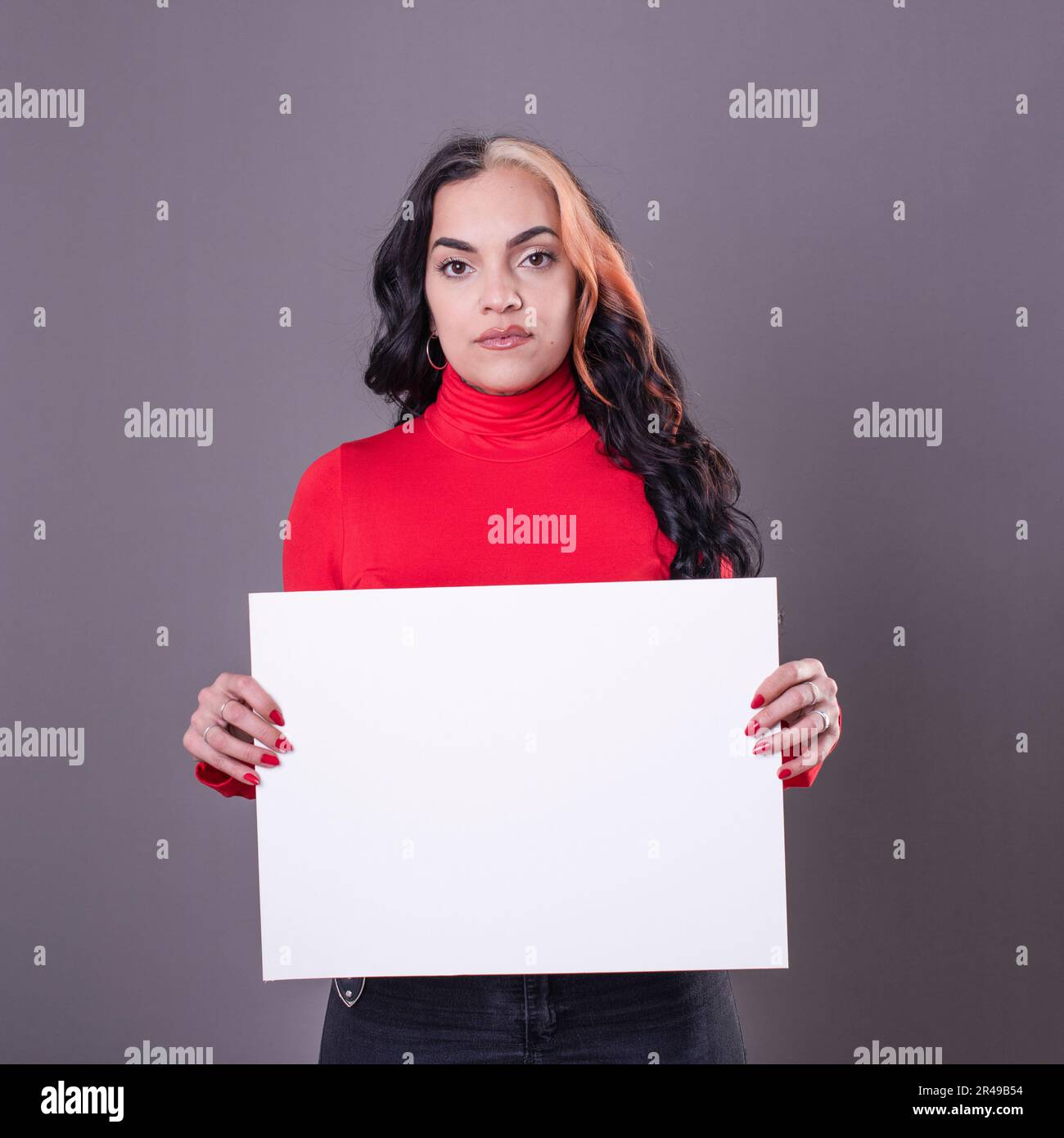 Bella donna che tiene un segno bianco su uno sfondo grigio Foto Stock