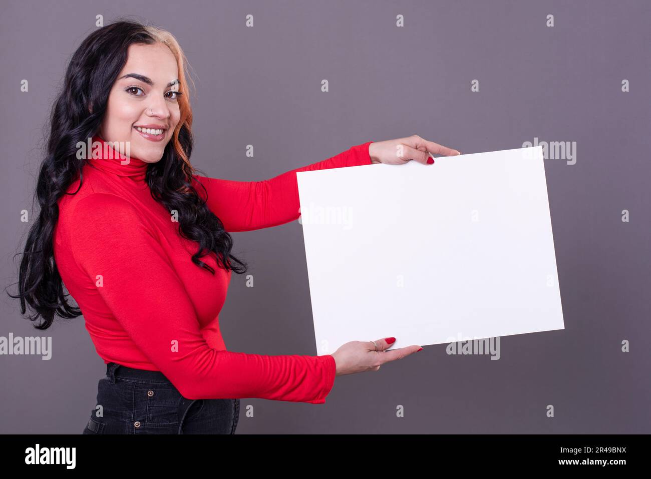 Bella donna che tiene un segno bianco su uno sfondo grigio Foto Stock