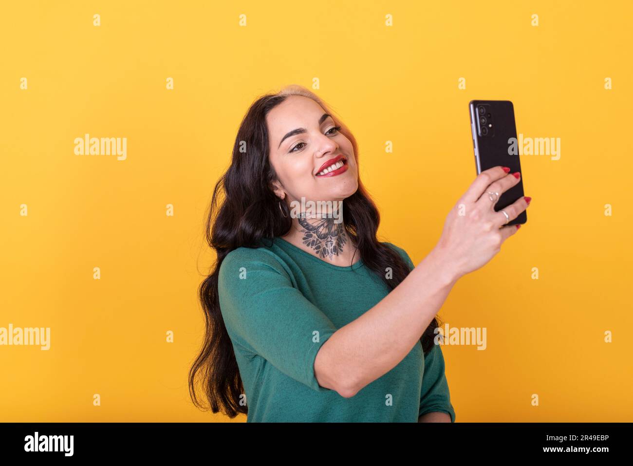 Ritratto di una donna attraente facendo un selfie su sfondo giallo. Foto da studio. Foto da studio. Foto Stock