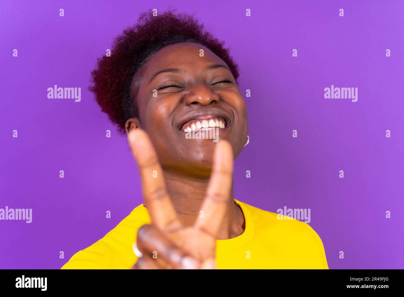 Un ritratto di una giovane donna nera allegra che mostra il segno di pace Foto Stock