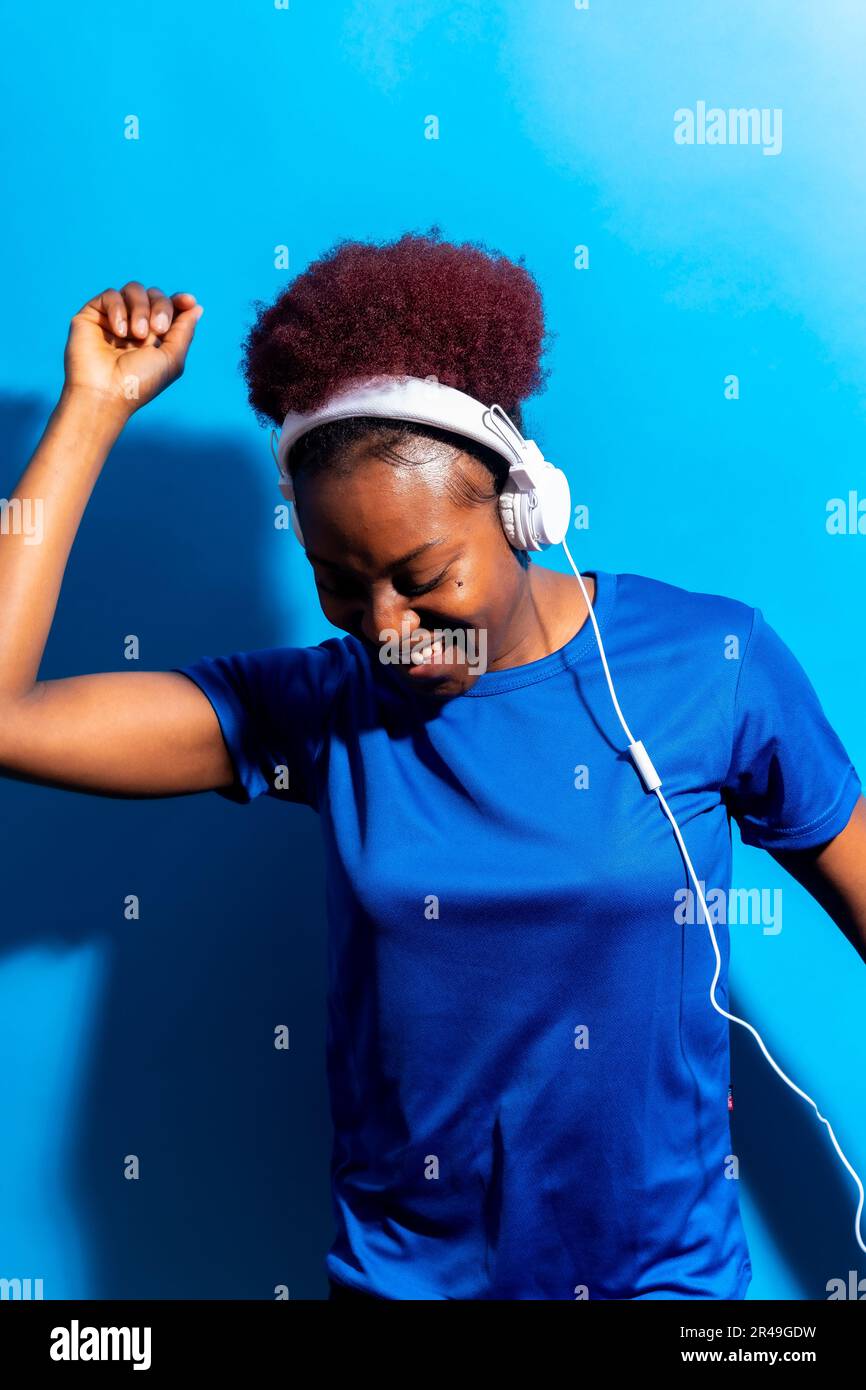 Un ritratto di una giovane donna nera allegra che ascolta musica con le cuffie Foto Stock