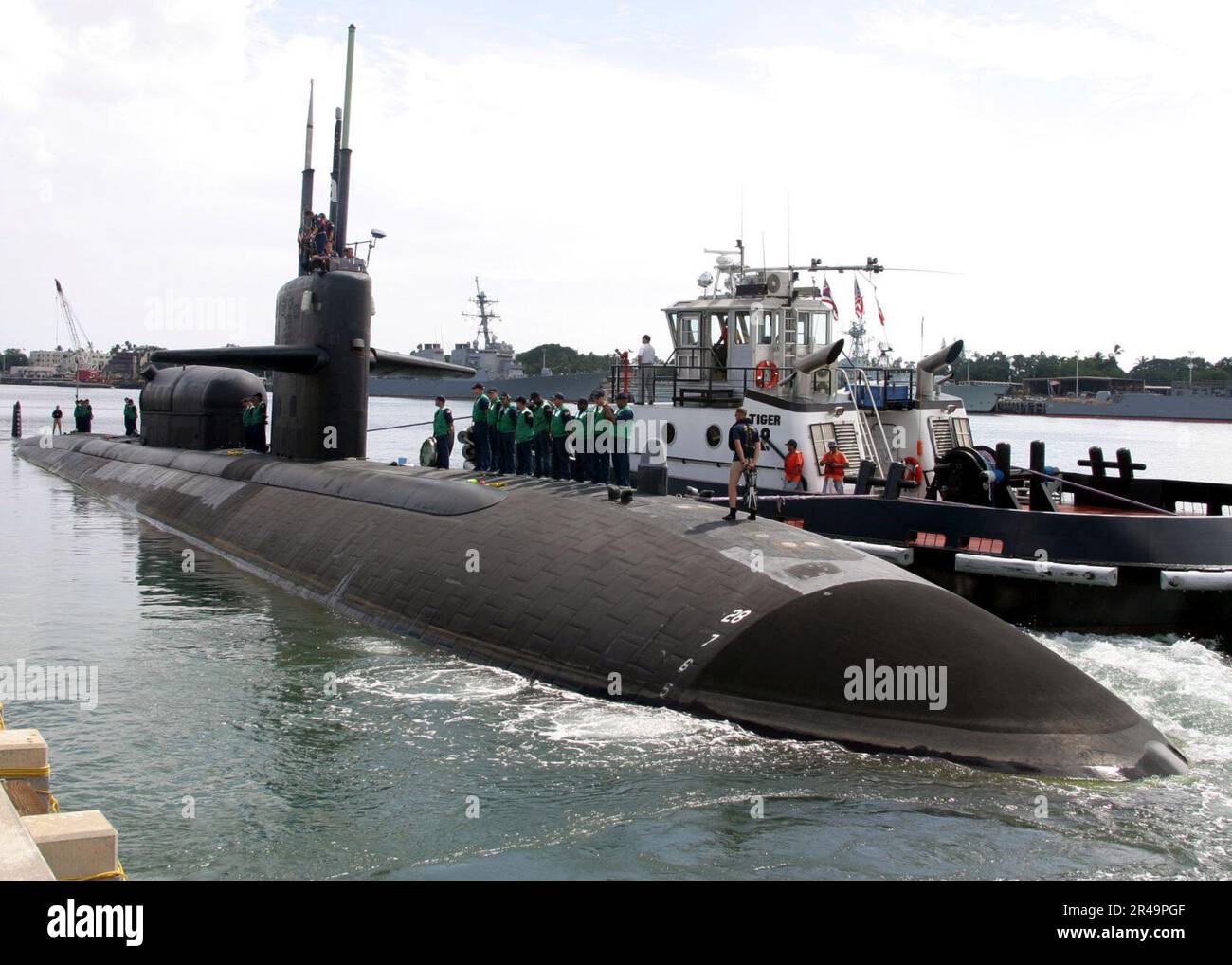 US Navy Un rimorchiatore guida delicatamente il sottomarino di attacco nucleare di classe Los Angeles USS la Jolla (SSN 701) lontano dal suo molo Foto Stock