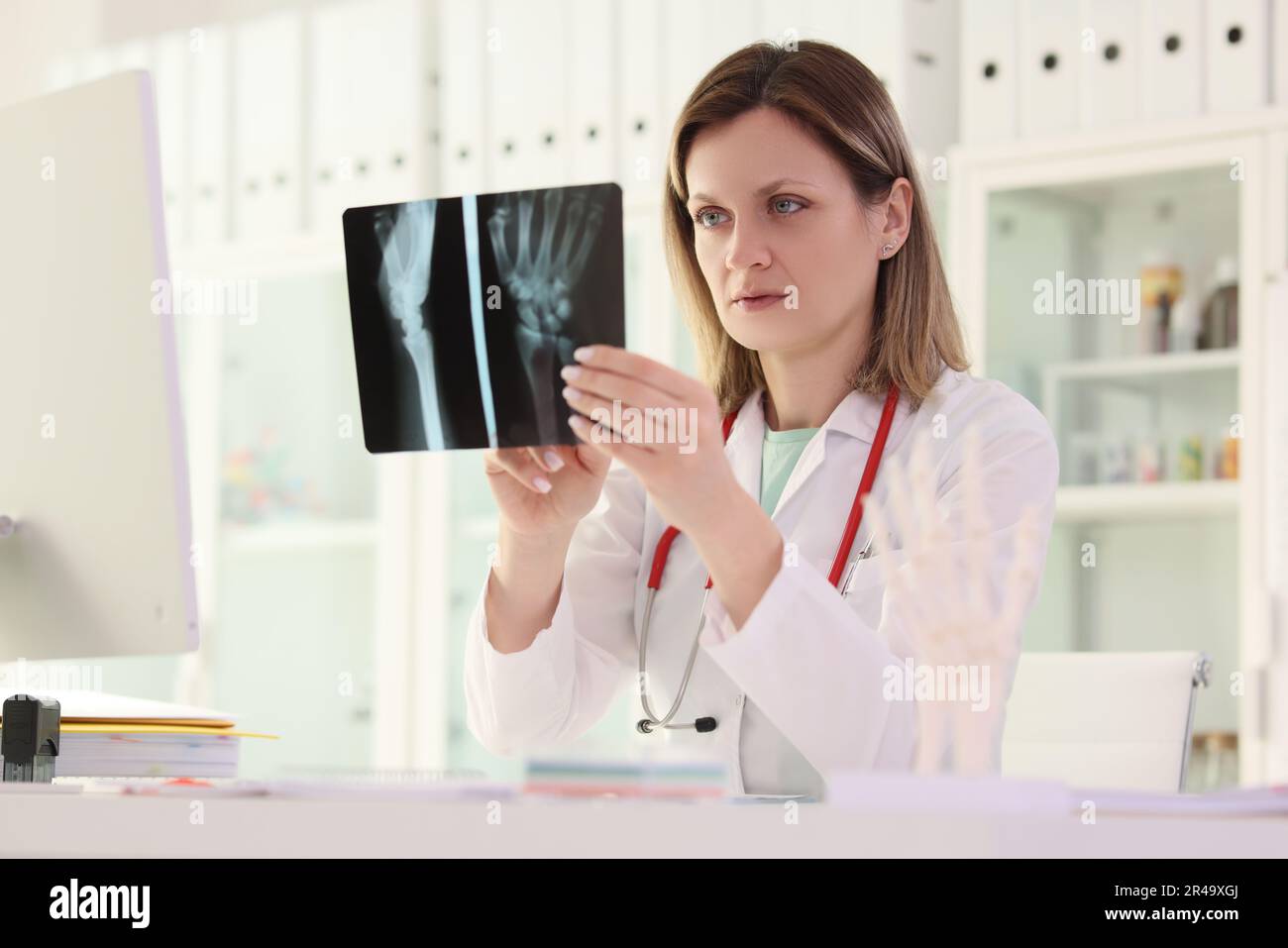 Il medico studia l'immagine radiografica del braccio del paziente seduto al tavolo Foto Stock