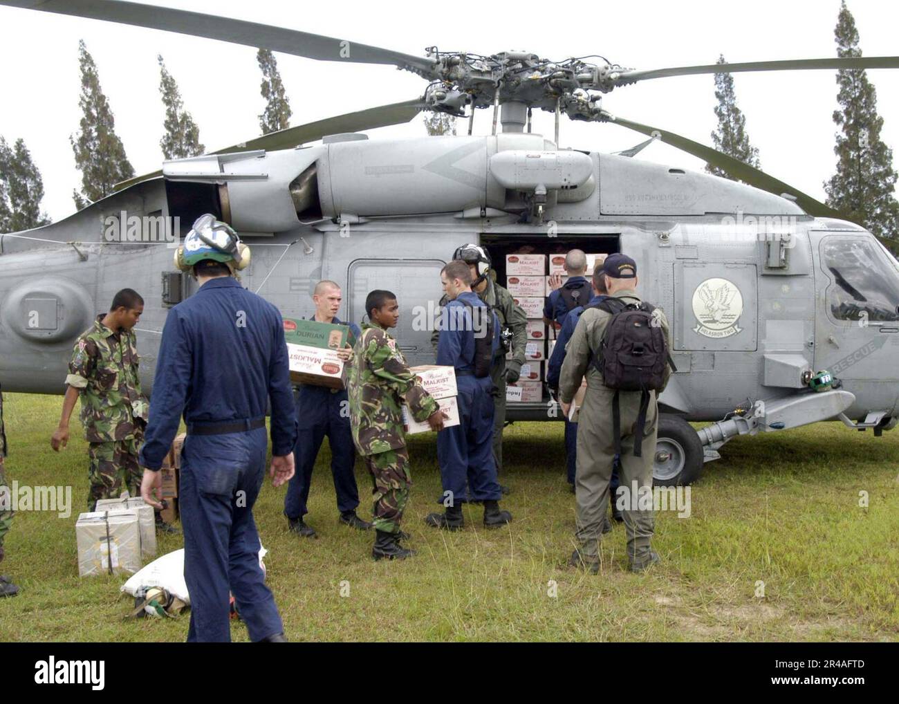 I marinai della Marina STATUNITENSE assegnati alla USS Abraham Lincoln (CVN-72) caricano le forniture in un elicottero HH-60H Seahawk, all'aeroporto Sultan Iskandar Muda di Sumatra, Indonesia Foto Stock