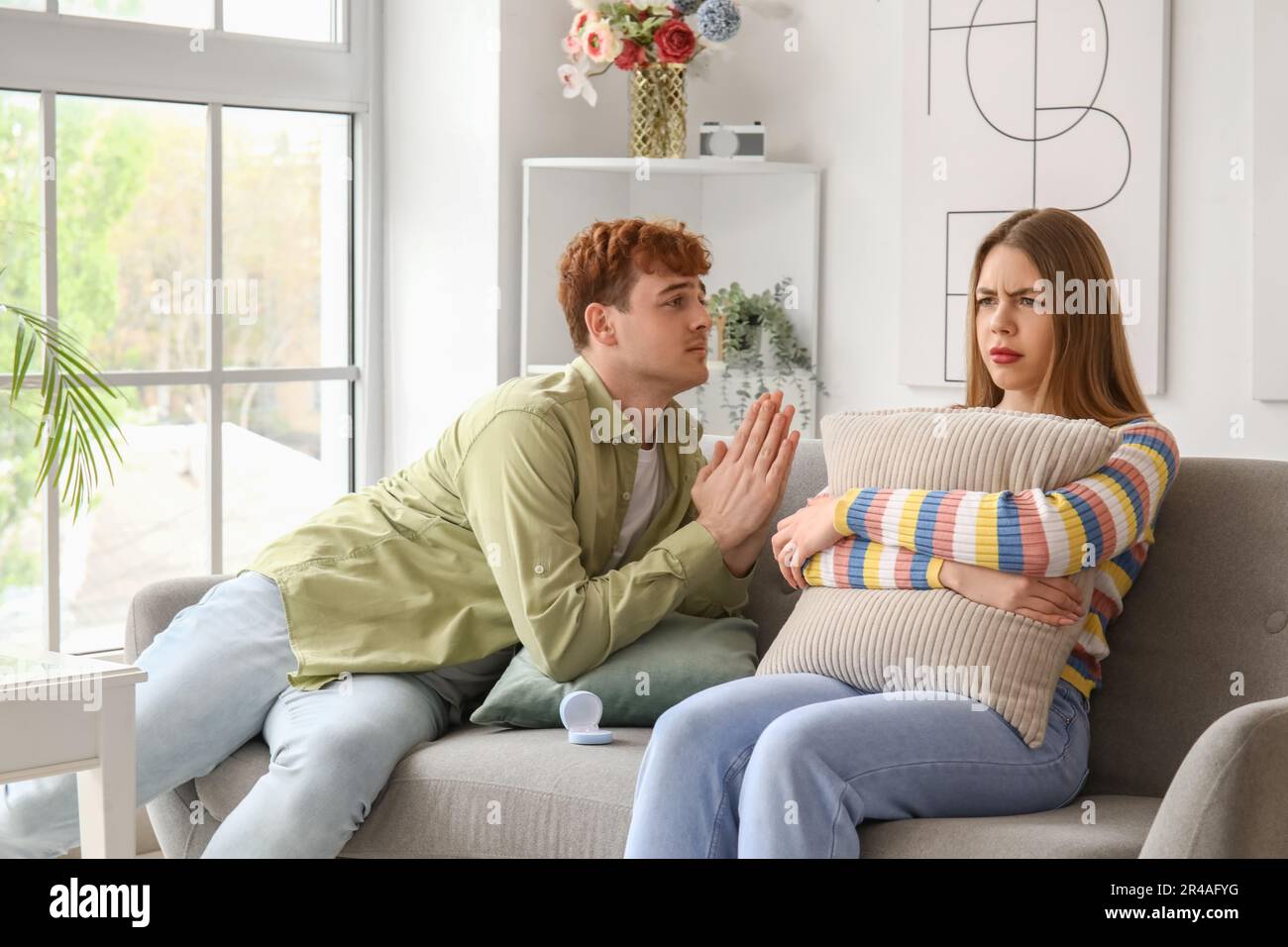 Giovane uomo che implora la sua fidanzata fidanzata di sposarlo a casa Foto Stock