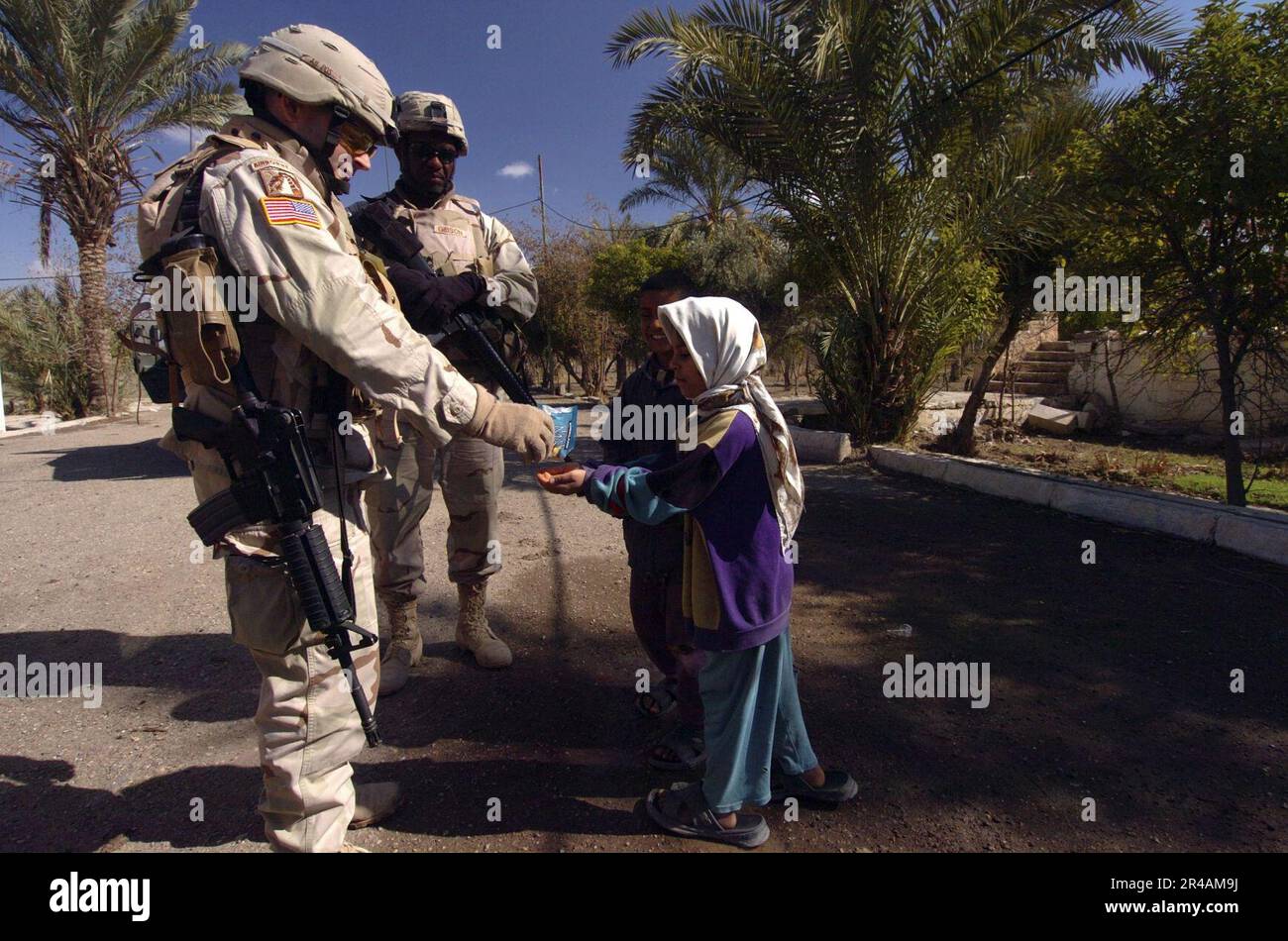 US NAVY A U.S. Militare Solider, assegnato alla squadra di combattimento di Brigate 256th (BCT), 2nd battaglione, distribuisce il mix di sentieri ai bambini locali mentre consegnano fertilizzanti agli agricoltori locali vicino a Baghdad, in Iraq Foto Stock